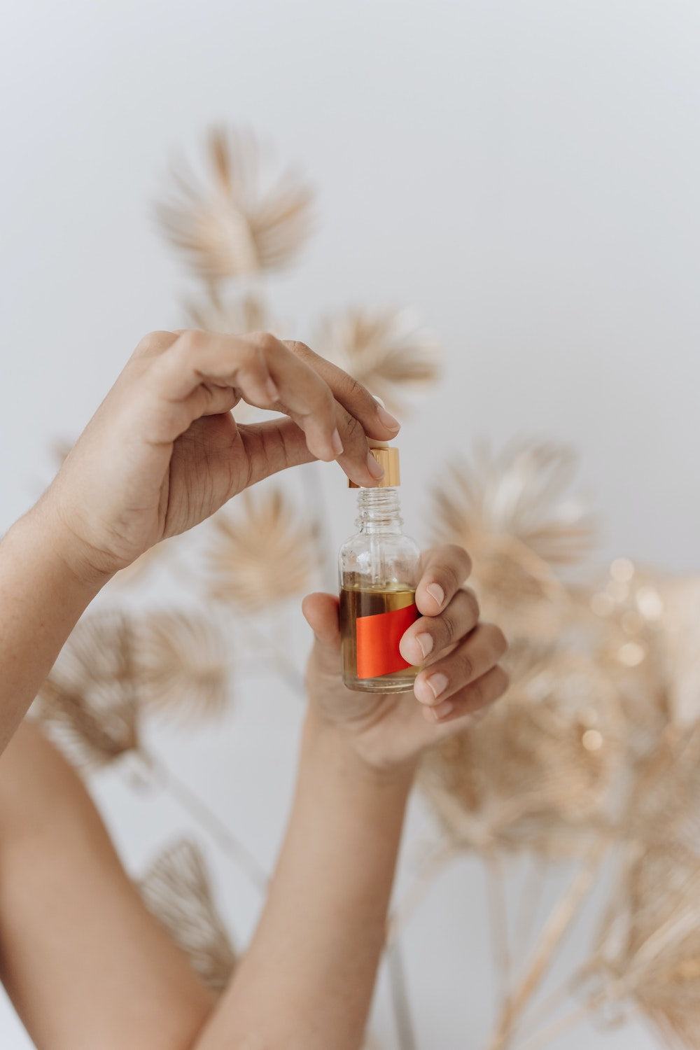 A woman holding a glass dropper of essential oil